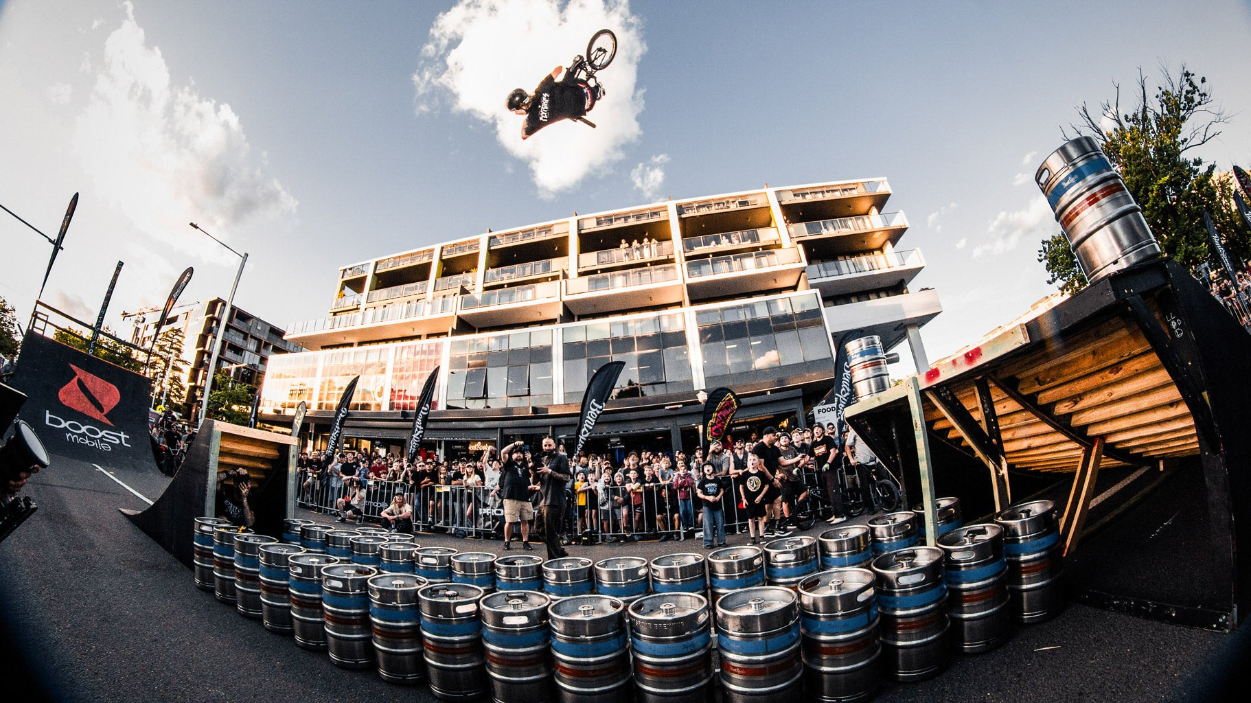 act jam 2025 braddon bmx event josh dove backflipping over lots of kegs with apartment building in backkground