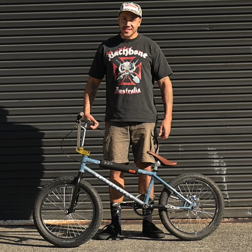 tyson jones-peni with his custom bmx bike a dark grey wethepeople chaos machine v2 frame with gold stem and brown eclat exile seat